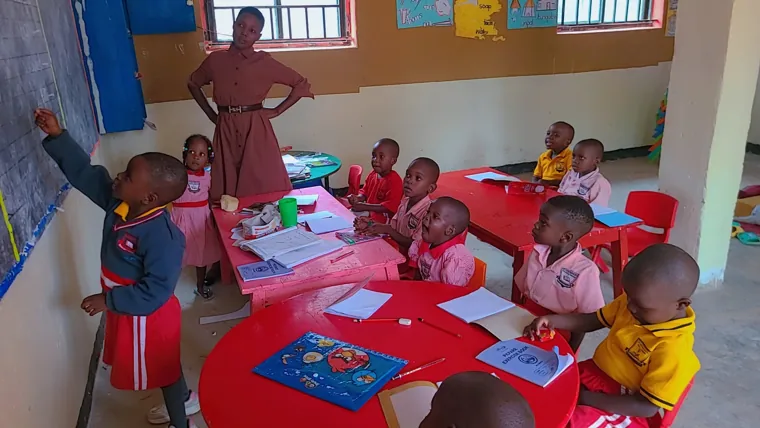 Children and their teacher around classroom tables