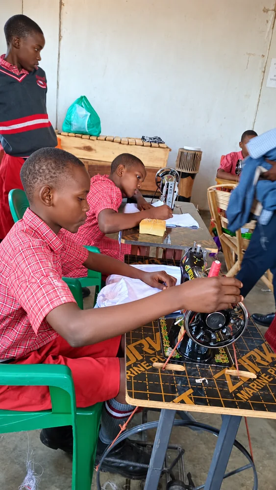 Pupils guiding fabric and turning the handwheel of a sewing machine