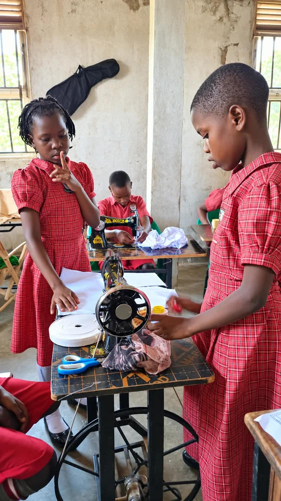 Girls working with fabric beside a sewing machine at St. Keren